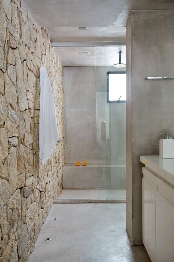 banheiro estreito revestido com pedra natural 
