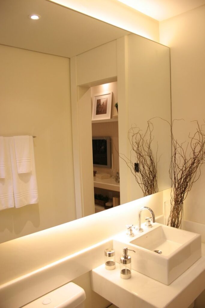 Banheiro Branco Com iluminação Led Amarela indireta atrás do espelho
