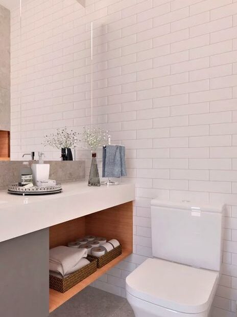 Banheiro Simples com azulejos brancos e detalhes amadeirado no gabinete 