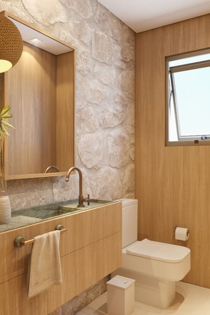 banheiro com iluminação amarelada e revestida com pedra natural 
